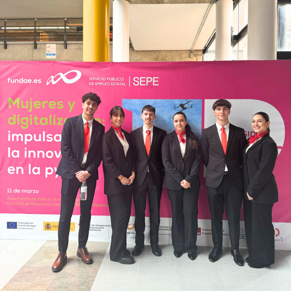Equipo de azafatos y azafatas frente al mural del evento Mujeres y Digitalización en Albacete.