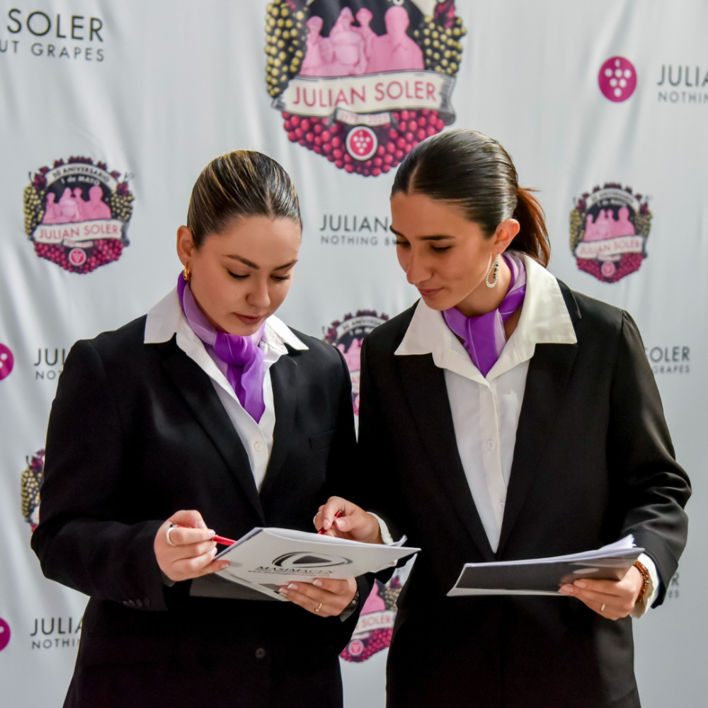 Azafatas de eventos revisando la escaleta frente al photocall de Julián Soler.